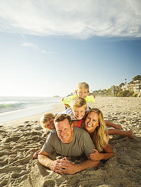 Portrait of smiling family with children (6-7, 10-11, 14-15) on beach, Laguna Beach, California