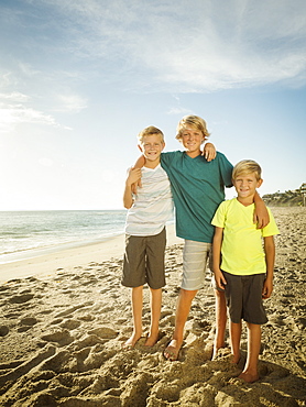 Portrait of brothers (6-7, 10-11, 14-15) on beach, Laguna Beach, California