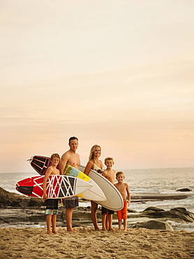 Portrait of family with three children (6-7, 10-11, 14-15) with surfboards on beach, Laguna Beach, California