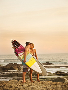 Mid-adult couple kissing on beach at sunset, Laguna Beach, California