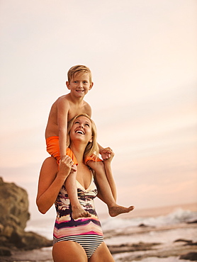 Mother carrying son (6-7) on shoulders outdoors, Laguna Beach, California