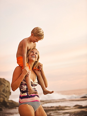 Mother carrying son (6-7) on shoulders outdoors, Laguna Beach, California