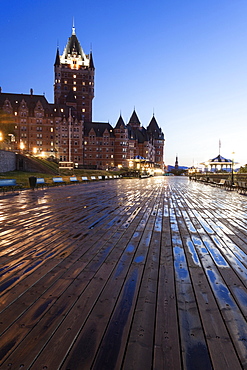 Low angle view of wooden pier and illuminated Chateau Frontenac at dawn, Quebec, Canada