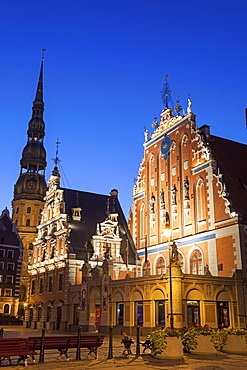 Illuminated House of the Blackheads and St. Peter's Church against blue sky, Latvia