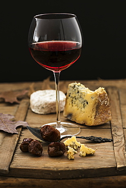 Still life with cheese and red wine on wooden table, studio shot