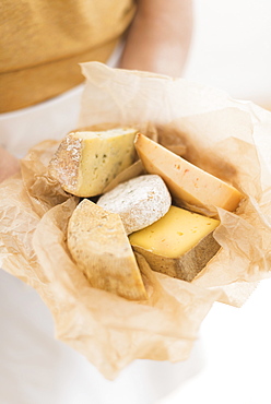 Close up of man's hand holding slices of cheese in paper