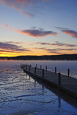 Jetty on frozen lake, hills in background at sunrise, Lake George, New York