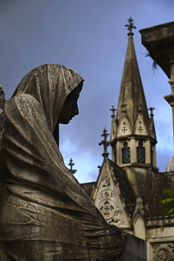 Close up of sculpture and church tower in Recoleta Cemetery, Recoleta Cemetery, Buenos Aires, Argentina