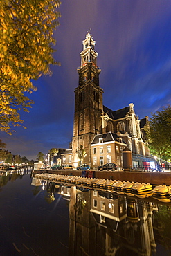 Illuminated Westerkerk Church reflecting in still canal , Westerkerk church, Amsterdam, North Holland, Netherlands