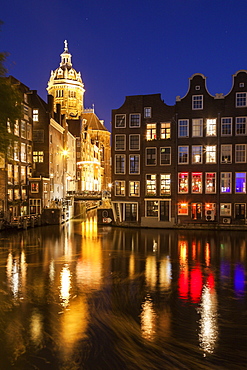 Illuminated buildings by canal at night, Amsterdam, North Holland, Netherlands