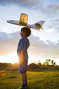 Boy (6-7) playing with model airplane outdoors, Colorado, USA