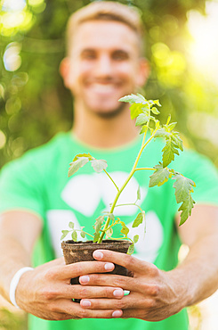 Portrait of young man holding potted plant