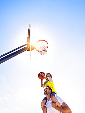 Boy (8-9) playing basketball with his brother