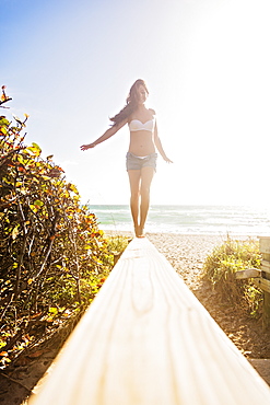 Young woman balancing on boardwalk, Jupiter, Florida,USA