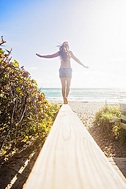 Young woman balancing on boardwalk, Jupiter, Florida,USA