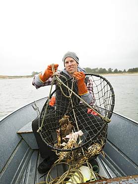 Portrait of man holding crabs in net, Rockaway Beach, Oregon