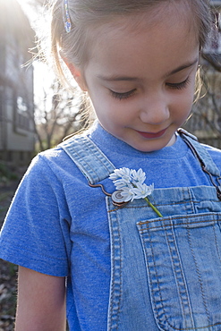 Girl with flower in overalls pocket