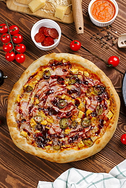 Pizza and ingredients on wooden table