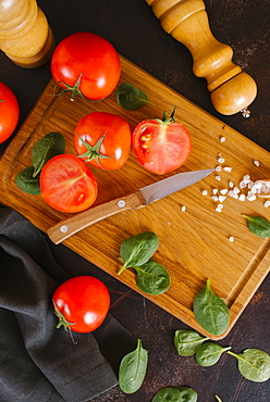 Tomatoes, basil and salt on wooden cutting board