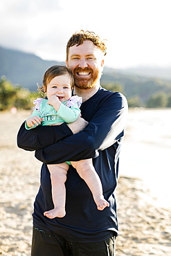 Man holding baby daughter on beach