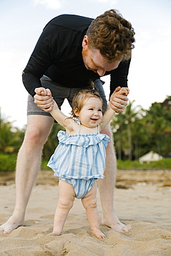 Man playing with baby daughter on beach