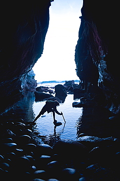 Teenage boy exploring care with rocks in La Jolla, California