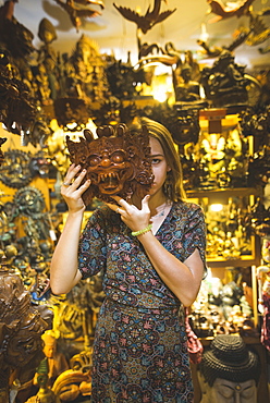 Young woman holding Barong mask in store in Bali, Indonesia