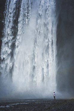 Man standing by Skogafoss waterfall in Iceland