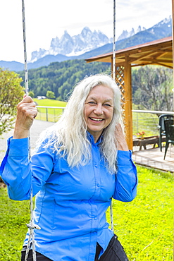 Mature woman smiling on swing, St. Peter, South Tyrol, Italy