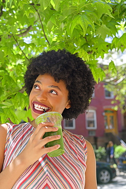 Woman drinking green juice under tree