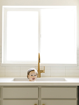 Baby girl bathing in kitchen sink