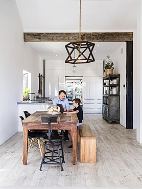 Father and son using digital tablet at dining table