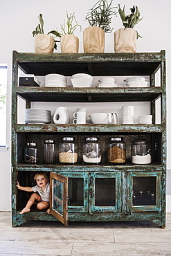 Boy hiding in cupboard in kitchen