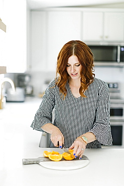 Woman slicing orange in kitchen