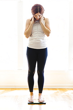 Mid adult woman weighing herself