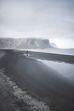 Man walking on black sand beach in Kirkjubµjarklaustur, Iceland