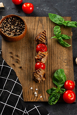 Grilled meat and tomato skewer on cutting board