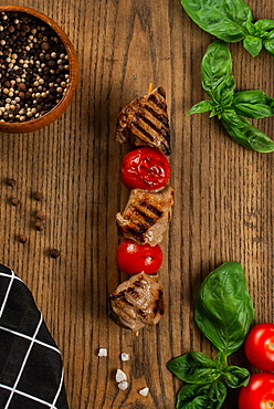 Grilled meat and tomato skewer on cutting board