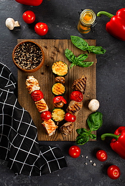 Grilled skewers on cutting board with vegetables