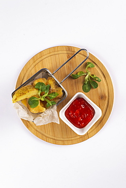 Fried potatoes with tomato sauce on cutting board