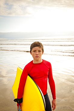 Boy holding body board on beach