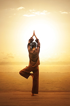 Woman doing yoga by beach in South Male Atoll, Maldives, South Asia