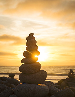 Stacked stones on beach at sunset