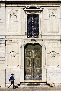 Woman walking past old building in Lisbon, Portugal