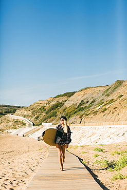 Woman holding surfboard on boardwalk