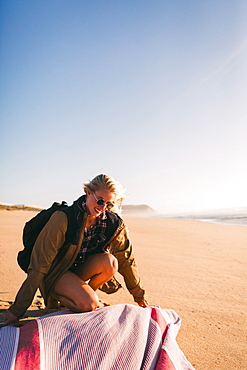 Smiling woman laying down towel on beach