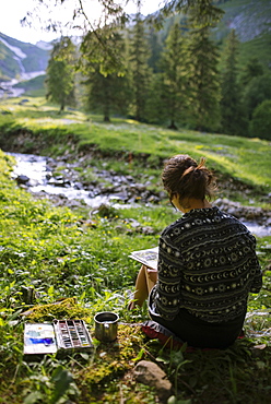 Woman painting with watercolors by river in Appenzell, Switzerland