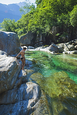 Woman wearing bikini on rock by river