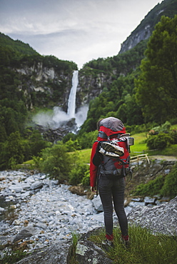 Woman wearing backpack with waterfall in distance