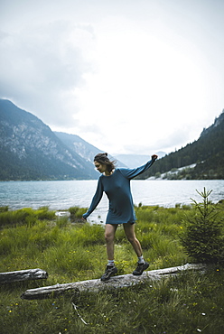 Young woman balancing on log by lake